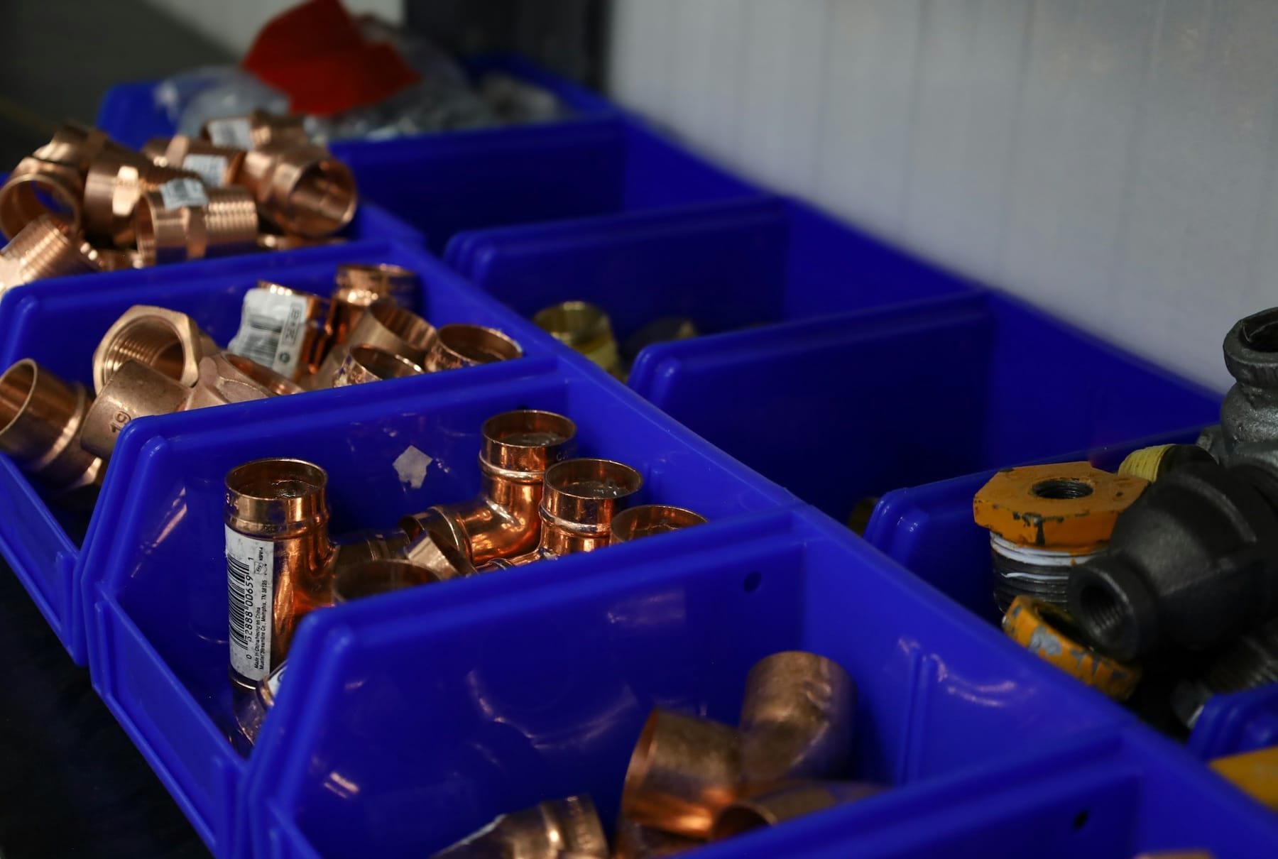 Copper and brass plumbing fittings sorted into blue parts bins.