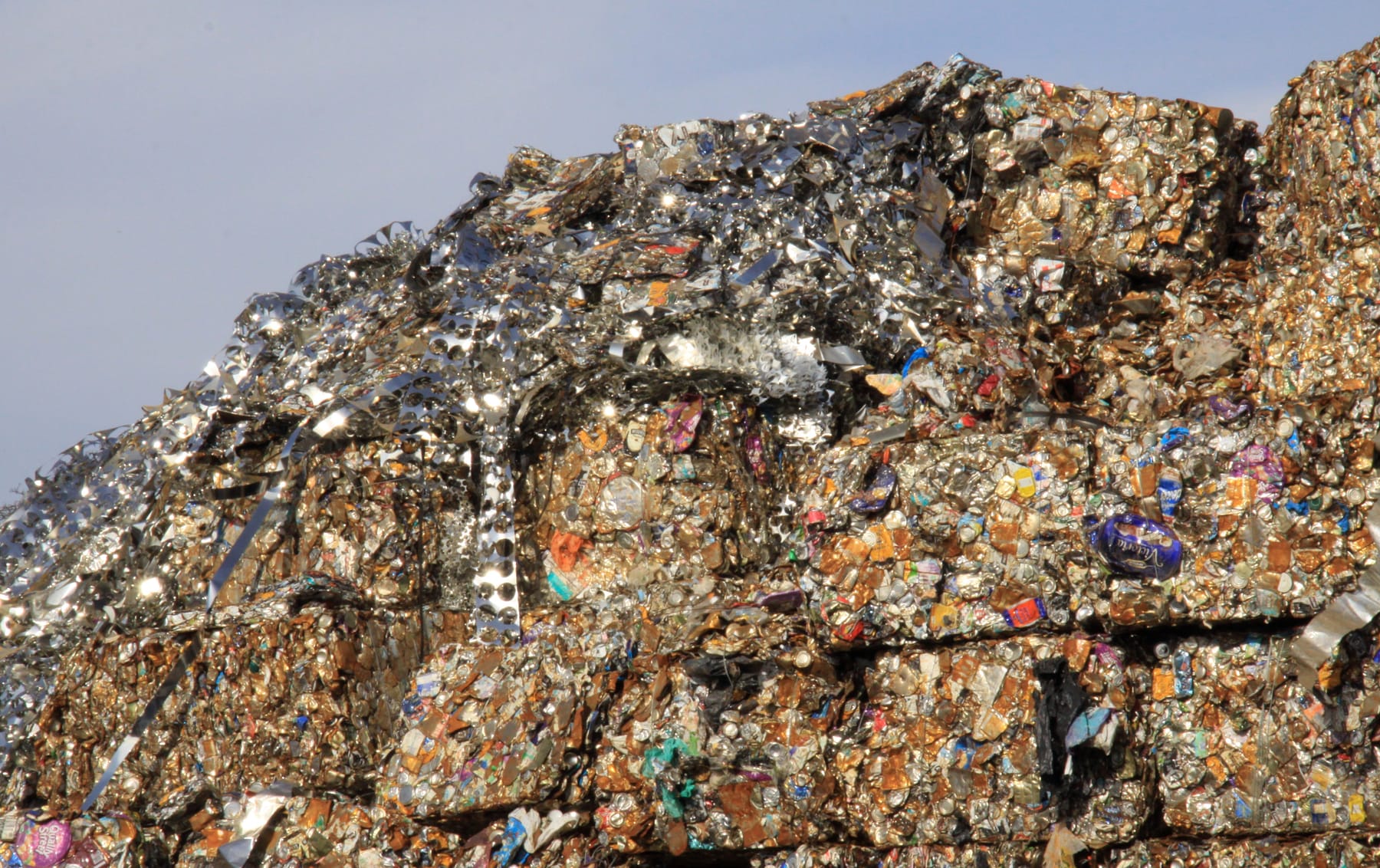 Baled scrap metal stacked several bales high against an open sky.