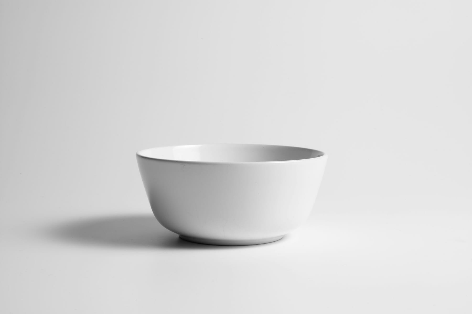 A single white ceramic bowl on a plain pale surface, lit evenly.
