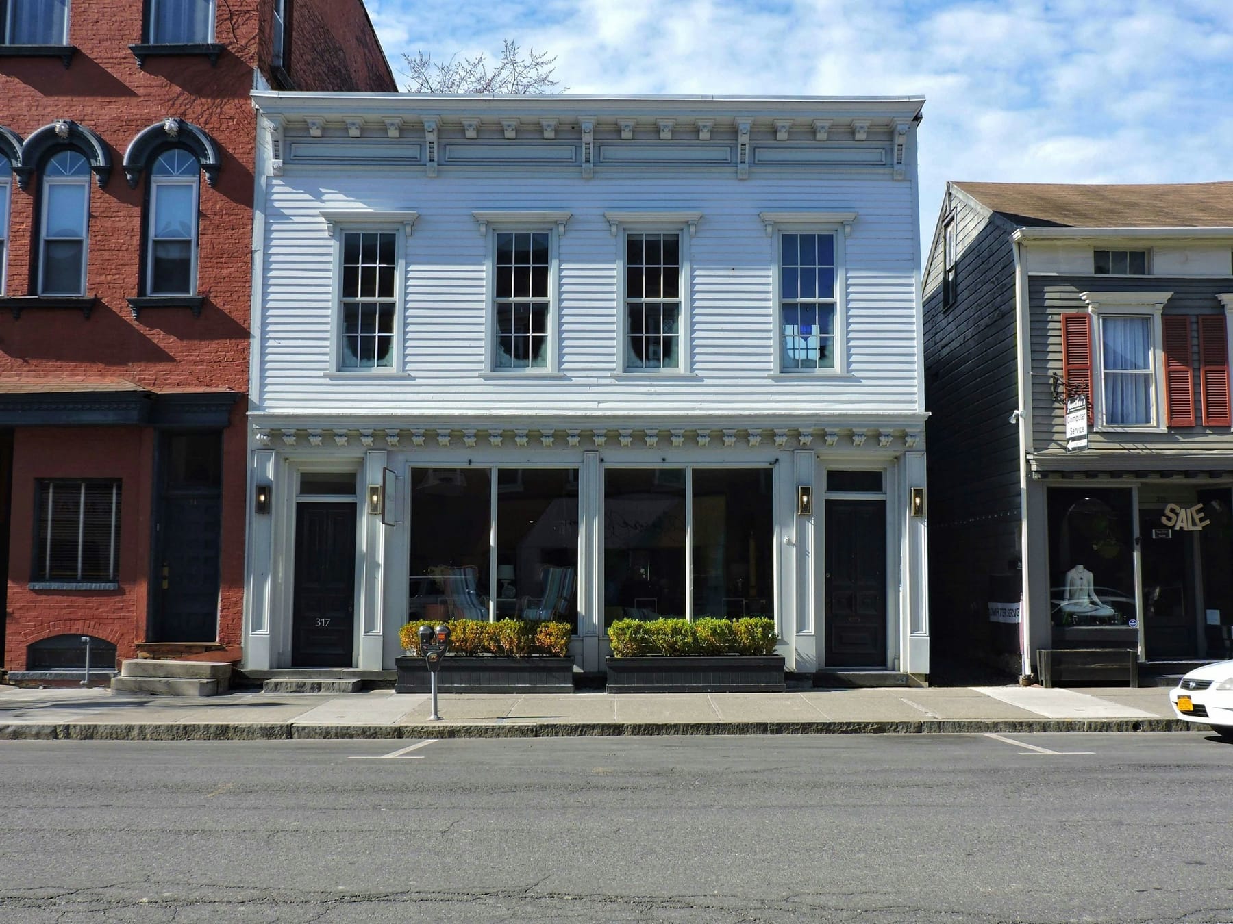 A modest two-storey storefront building on a quiet street, with large ground-floor windows.