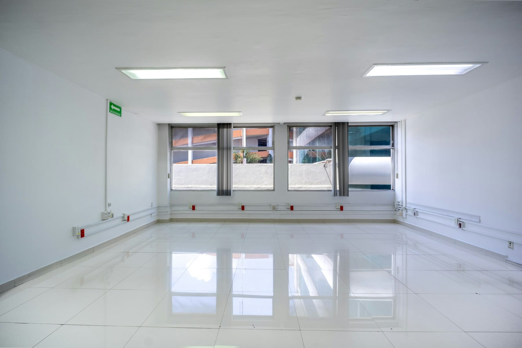 An empty commercial room with a polished floor and a bank of windows, finished and ready for handover.