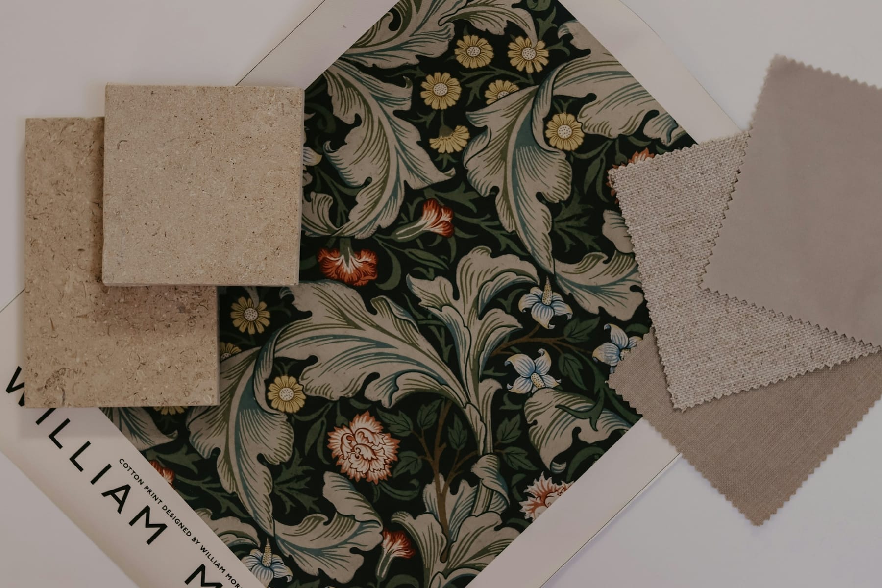 Wallpaper, stone and fabric samples laid out overlapping on a table.